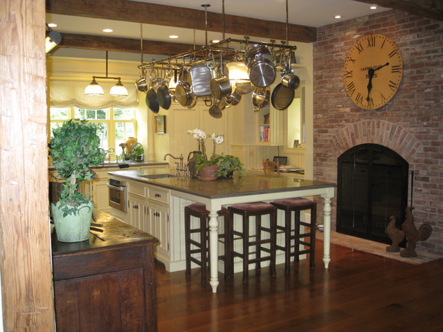 Designs by Dolores - Kitchen with wood floors, white cabinets and pot hanger above center island